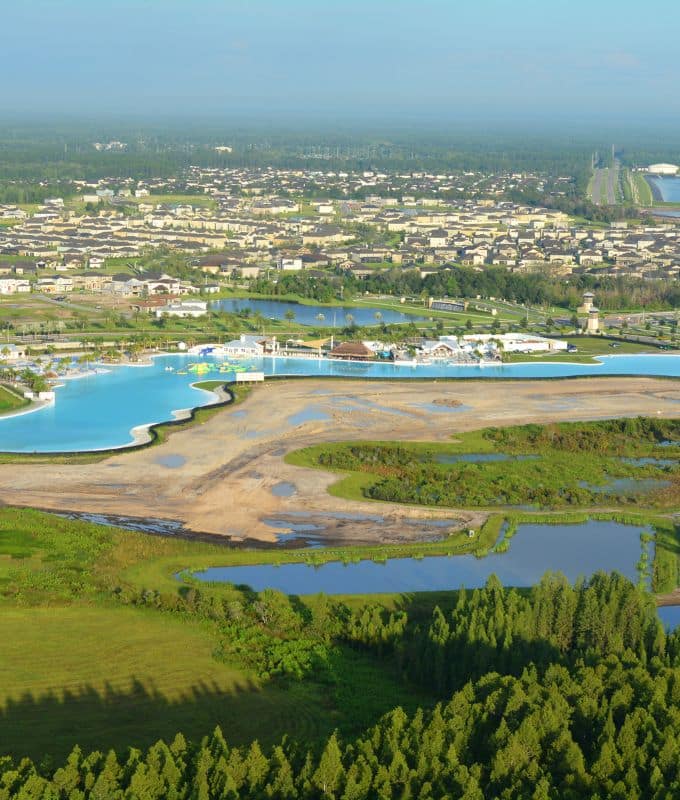 Aerial view of a scenic lagoon and residential area in Wesley Chapel, Florida, surrounded by lush greenery and nearby developments.