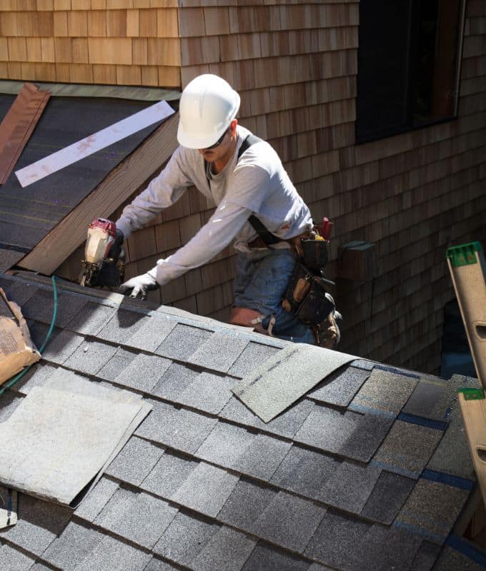 Professional roofing contractor securing shingles during a roof installation project on a home.